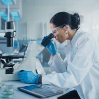 Image of a researcher looking into a microscope in a scientific lab